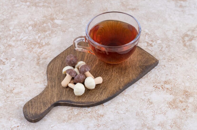 A cup of hot tea with sweet mushrooms on a wooden board