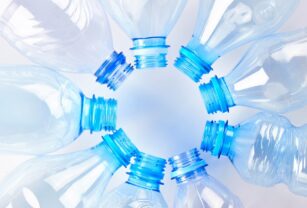 Set of empty different type water bottles lie isolated on white, top view. Plastic production and processing concept