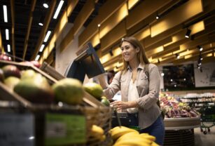 Woman at supermarket using self service digital scale to measure the weight of fruit.